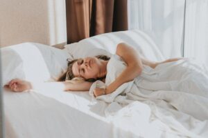 Person sover lugnt i en ljus säng med vitt täcke