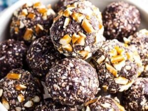 Mörka hemgjorda energibollar täckta med hackade nötter