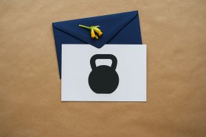 Kvinna på löpband med träningskläder, håller i smartphone med e-postikon